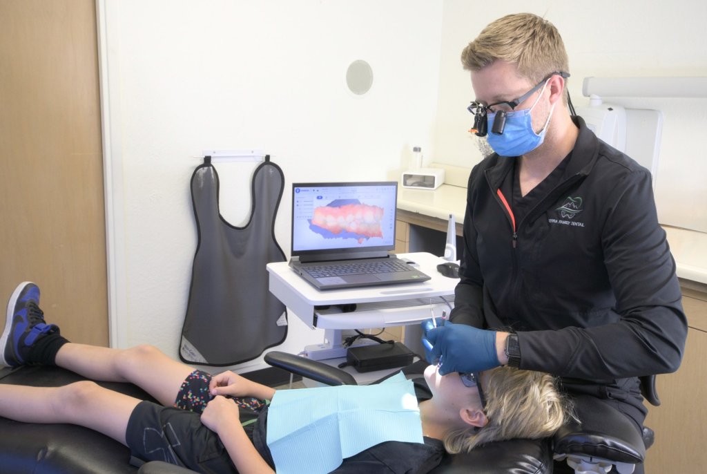 {LAST_NAME} seated at the exam chair with a young dental patient