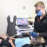 {LAST_NAME} seated at the exam chair with a young dental patient